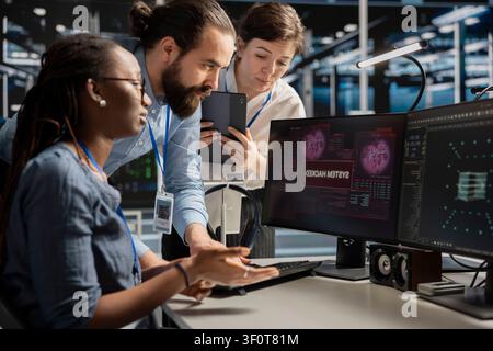 Engineering team reviews a security breach alert for a zero-day vulnerability inside a high-tech server room. Stock Photo