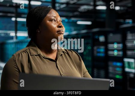 Coder doing maintenance on server facility electronics processing large datasets. Server environment staff member doing backups to protect infrastructure used by cloud storage hosting companies. Stock Photo