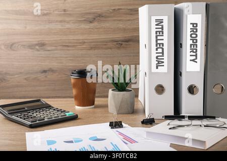 Intellectual property. Folders, documents and stationery on wooden table Stock Photo