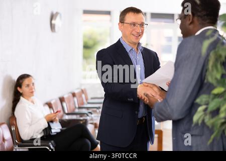 Two adult man shaking hands in reception Stock Photo