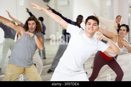 Cheerful guy practicing modern vigorous dance with group Stock Photo