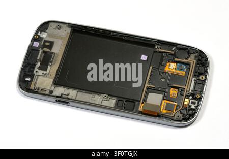 Disassembled old smartphone with no battery and exposed internal components, isolated on white background, mobile phone repair parts, electronics recy Stock Photo