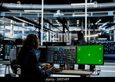 Server facility expert working with AI programming tools on green screen workstation to set up specialized hardware. Stock Photo