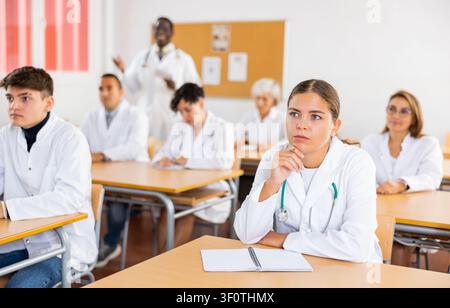Doctors different age sitting at desk in classroom working during lesson at education class Stock Photo