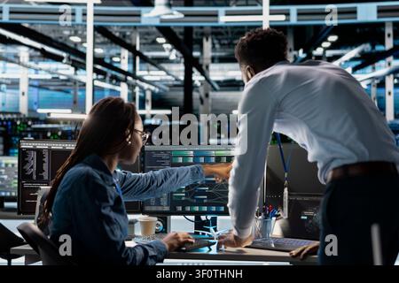 Data center technician team oversees machine learning system setup, guiding an engineer and neural network training for server operations. Stock Photo