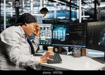 Tired engineer in pain suffering from headache while setting up server room equipment needed to run AI. Stock Photo