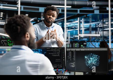 Data center manager supervising engineer reviewing data analysis graph to reduce failures. Stock Photo