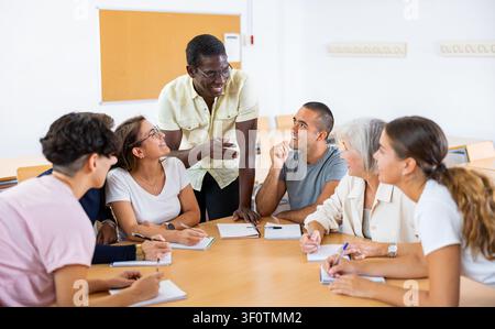 Multiracial mixed age group participating adult education class with African American tutor Stock Photo