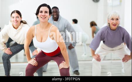 Smiling young woman rehearsing modern dance with group in dance school Stock Photo