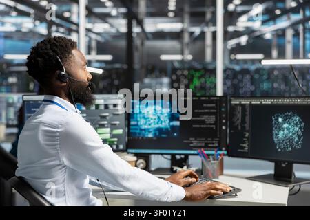 Employee talking in headset mic with technicians setting up server room equipment needed to run AI. Stock Photo