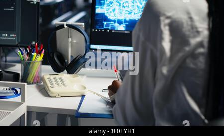 Female technician answers a phone call in a server hub, using an AI assistant to provide technical support to users. Stock Photo