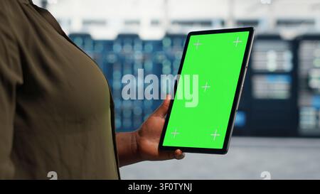Data center administrator works with a chroma key tablet, using an editable screen to expand workload capacity. Stock Photo