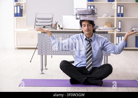 Young handsome male employee doing exercises in the office Stock Photo