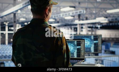 Military IT specialist reviews reconnaissance information with AI software in a server room environment. Stock Photo