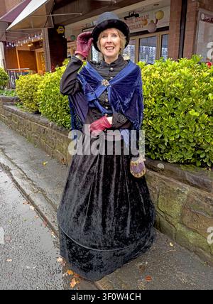 Smiling festival lady participant wears Victorian period dress during Lymm Dickensian Weekend in Cheshire, England, December 2023. Stock Photo