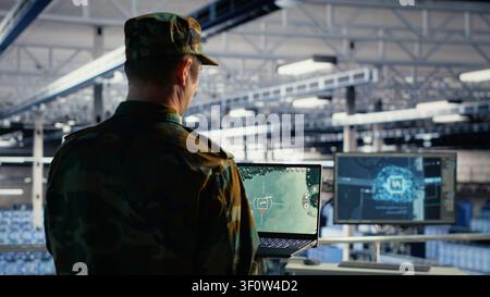 Military technician in a military data center monitors satellite coordinates with radar software, scanning aerial activity for defense operations. Stock Photo