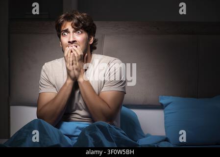 Young man scared in his bed having nightmares Stock Photo