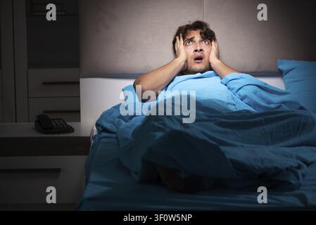 Young man scared in his bed having nightmares Stock Photo