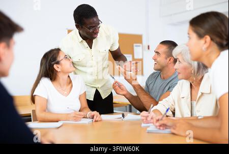 Multiracial mixed age group participating adult education class with African American tutor Stock Photo