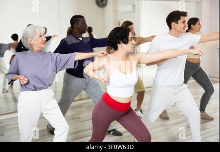 Smiling young woman rehearsing modern dance with group in dance school Stock Photo