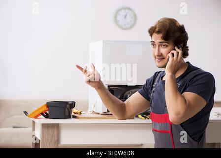 Young handsome contractor repairing fridge Stock Photo