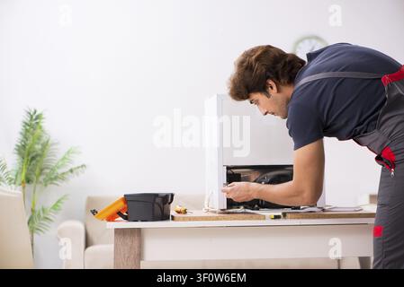 Young handsome contractor repairing fridge Stock Photo
