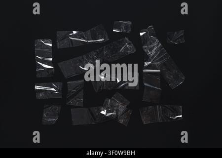 Clear adhesive tape pieces with wrinkles and air bubbles on a dark black background, abstract texture and grunge overlay Stock Photo