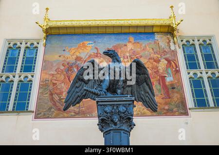 Bronze Eagle Statue with open wings on Stolzenfels Castle Facade in Germany, featuring beautiful historic fresco Painting and golden Gothic Canopy Stock Photo
