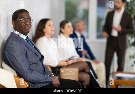 Applicants are waiting for interview, there is queue of people sitting in waiting room. Stock Photo
