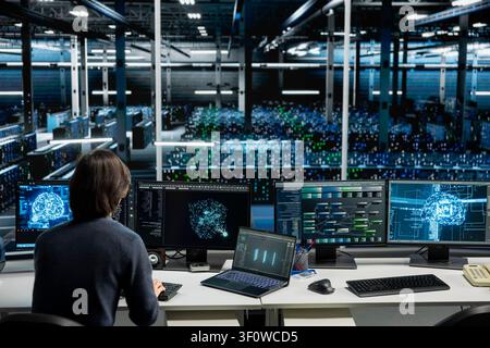 IT specialist working with computer in high tech computing hub with equipment supporting deep learning scientific simulations with computer scientist in server facility doing checkup on rackmounts. Stock Photo