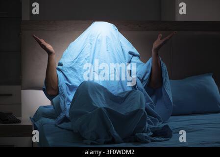 Young man scared in his bed having nightmares Stock Photo
