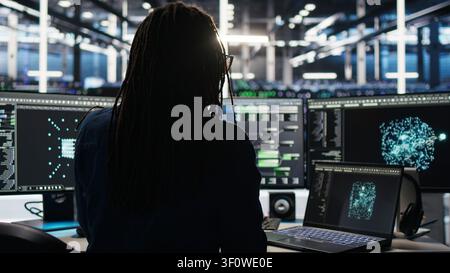 Data center technician arriving in office, working with AI visualization insights on computer to improve system health. Stock Photo