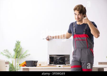 Young handsome contractor repairing fridge Stock Photo