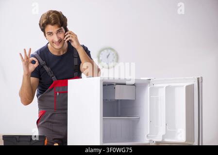 Young handsome contractor repairing fridge Stock Photo