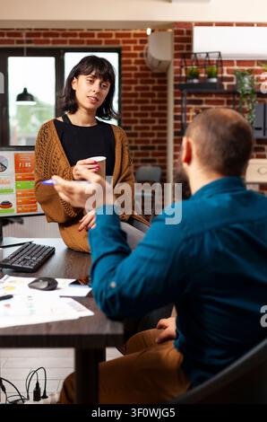 Executive manager talking with entrepreneur woman discussing marketing strategy illustrates project planning, communication and company workflow with laptop details in a professional office workspace. Stock Photo