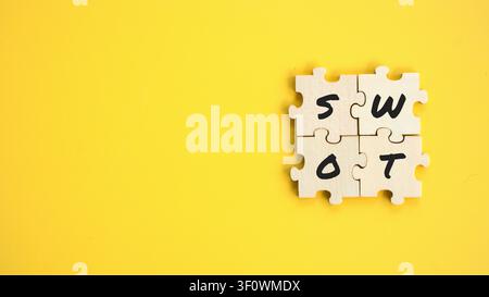 SWOT Matrix Concept Written on Four Jigsaw Puzzle Pieces Arranged in Square on Yellow Background Stock Photo