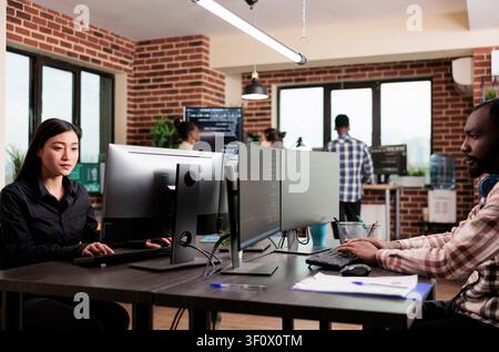 Diverse software developers program encryption applications, upgrading database systems and data processing tools for cybersecurity protection. Stock Photo