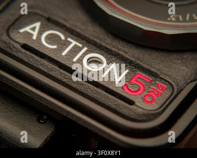 Macro extreme close-up shot of the white and red Action 5 Pro logo engraved text on a black textured digital camera body Stock Photo