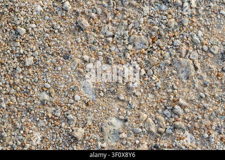 Detailed close-up of a seamless pattern featuring natural gravel, small stones, and sand. This textured background showcases a mix of earthy tones, pe Stock Photo