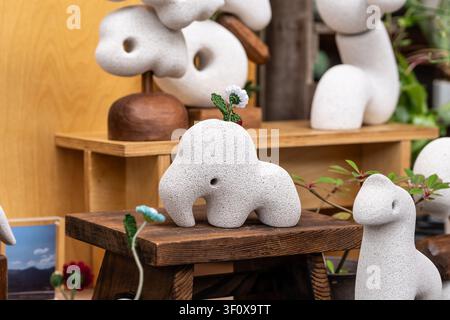 Chiang Mai, Thailand - 27th May 2026: A textured stone-look ceramic elephant figurine sits on a small wooden stool at an outdoor craft market Stock Photo