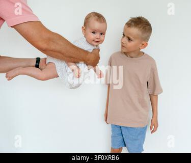 a serene and intimate family portrait capturing a baby being held by an adult in a side view close-up, set against a plain white background Stock Photo