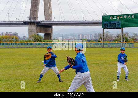 New Taipei City, Taiwan - Jan 20, 2026: Xinggu Elementary baseball team practices throwing and catching near a scoreboard Stock Photo
