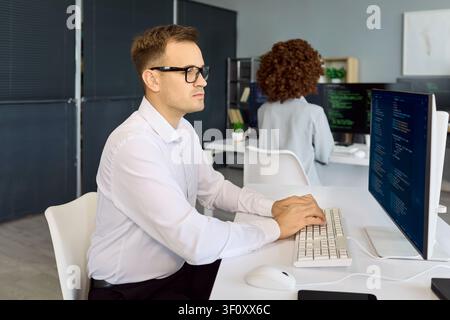 Programmers working on code in tech office with computers screens and teamwork Stock Photo