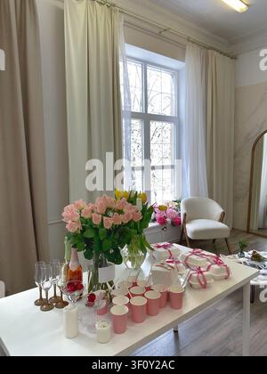 Elegant bridal shower table with flowers and desserts in bright modern event space. Stock Photo