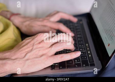 Close-Up of Hands Typing on Laptop Keyboard at Home Stock Photo