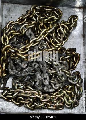 Chains resting, in metal surface, with chains, with metal texture, from a top-down perspective, with silver, greenish-brown accents, and industrial mo Stock Photo