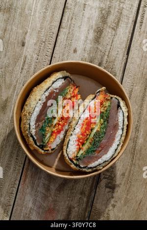 Sushi burger in a delivery box on a wooden background. Isolated. Artistic photo. Professional studio lighting. Stock Photo
