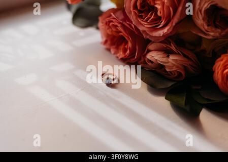 Rose gold engagement ring next to a bridal bouquet Stock Photo