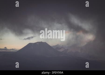 Dramatic storm clouds rolling over mountain peaks Stock Photo