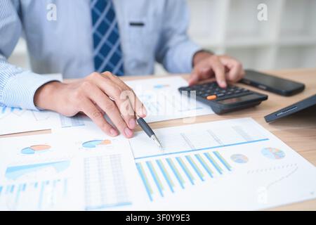 Businessman Analyzing Financial Data with Calculator and Reports Stock Photo